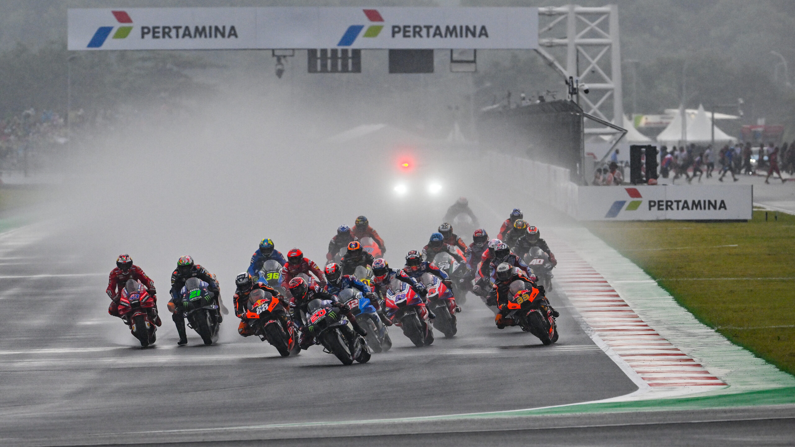 Riders accelerating at the start of the MotoGP Indonesian Grand Prix at Pertamina Mandalika Circuit, showcasing thrilling race action.